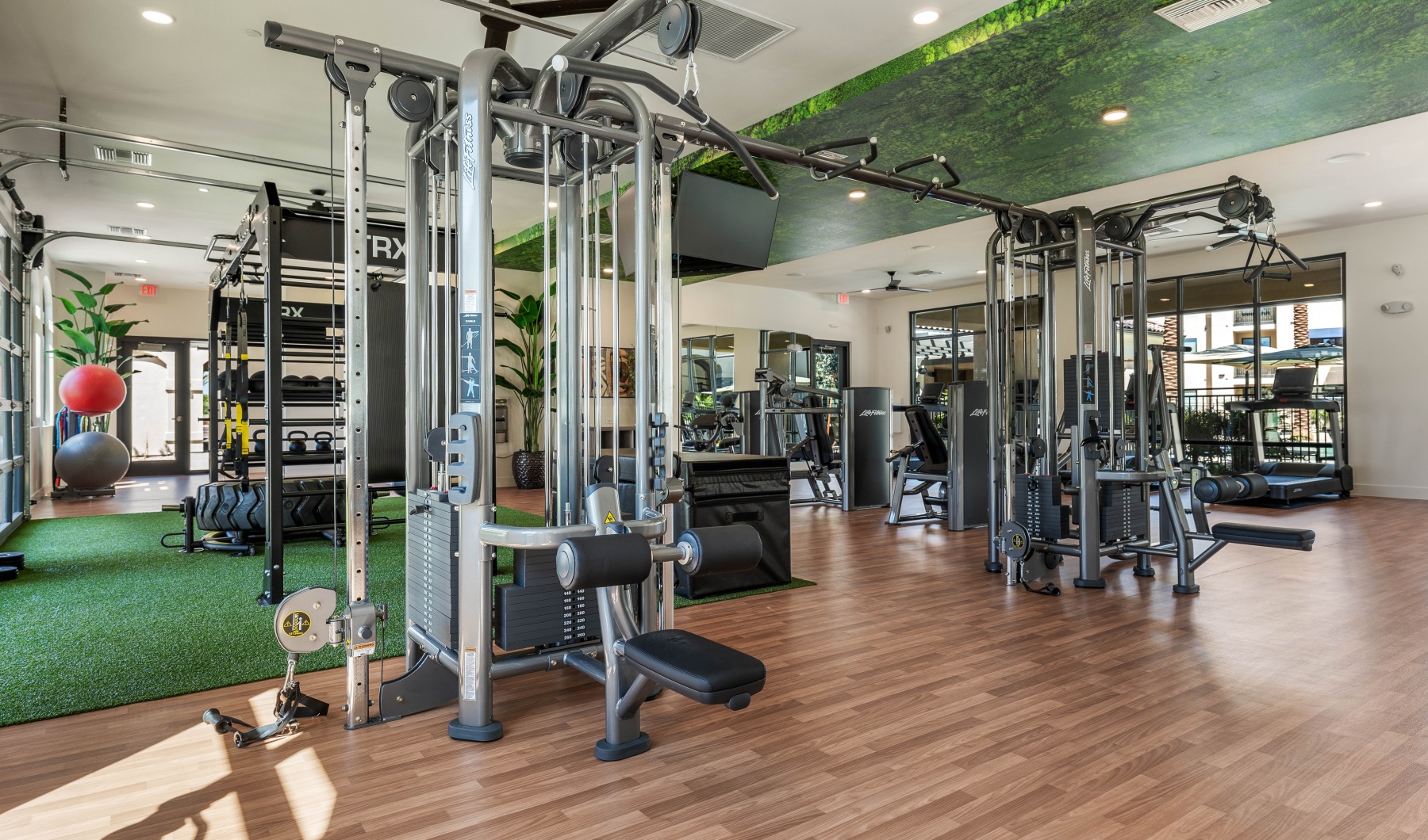 fitness center with cardio and weight training equipment and garage door with turf reaching to the exterior space